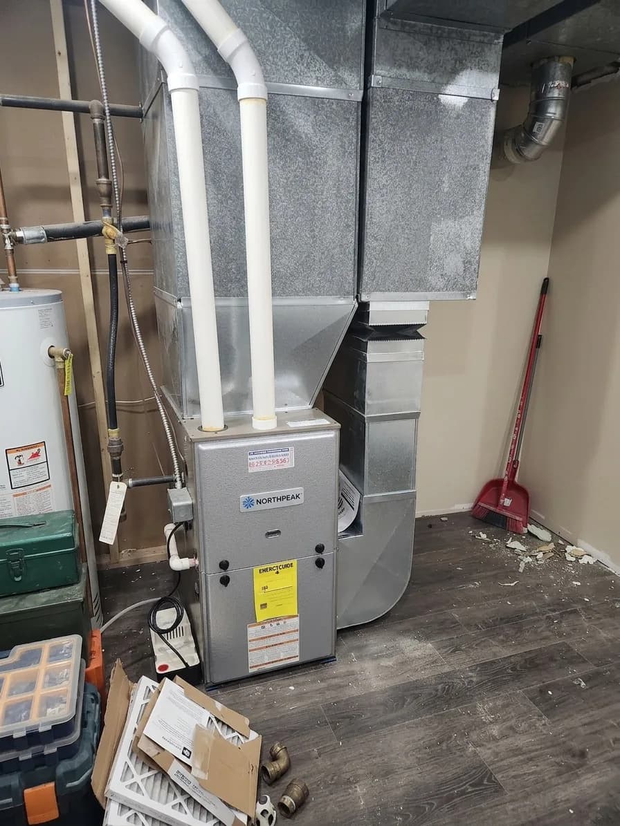 High-efficiency residential furnace with clean ductwork in a finished basement.