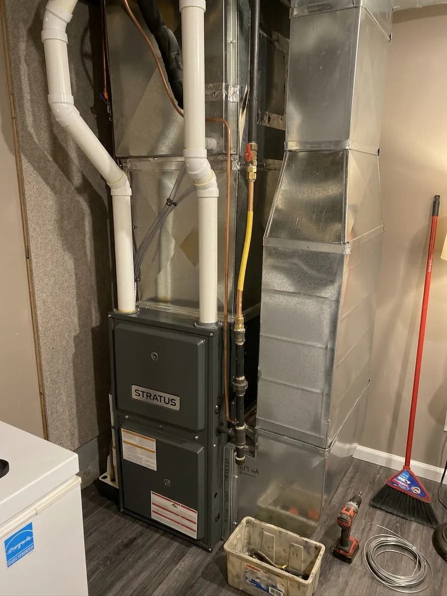 High-efficiency furnace upgrade in a residential utility area with PVC venting.