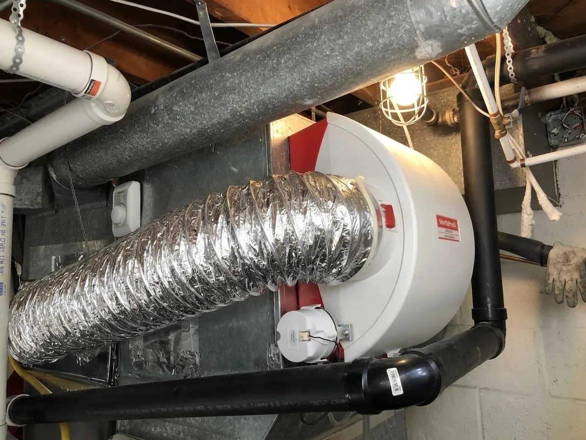 Heat recovery ventilator mounted to a basement ceiling.
