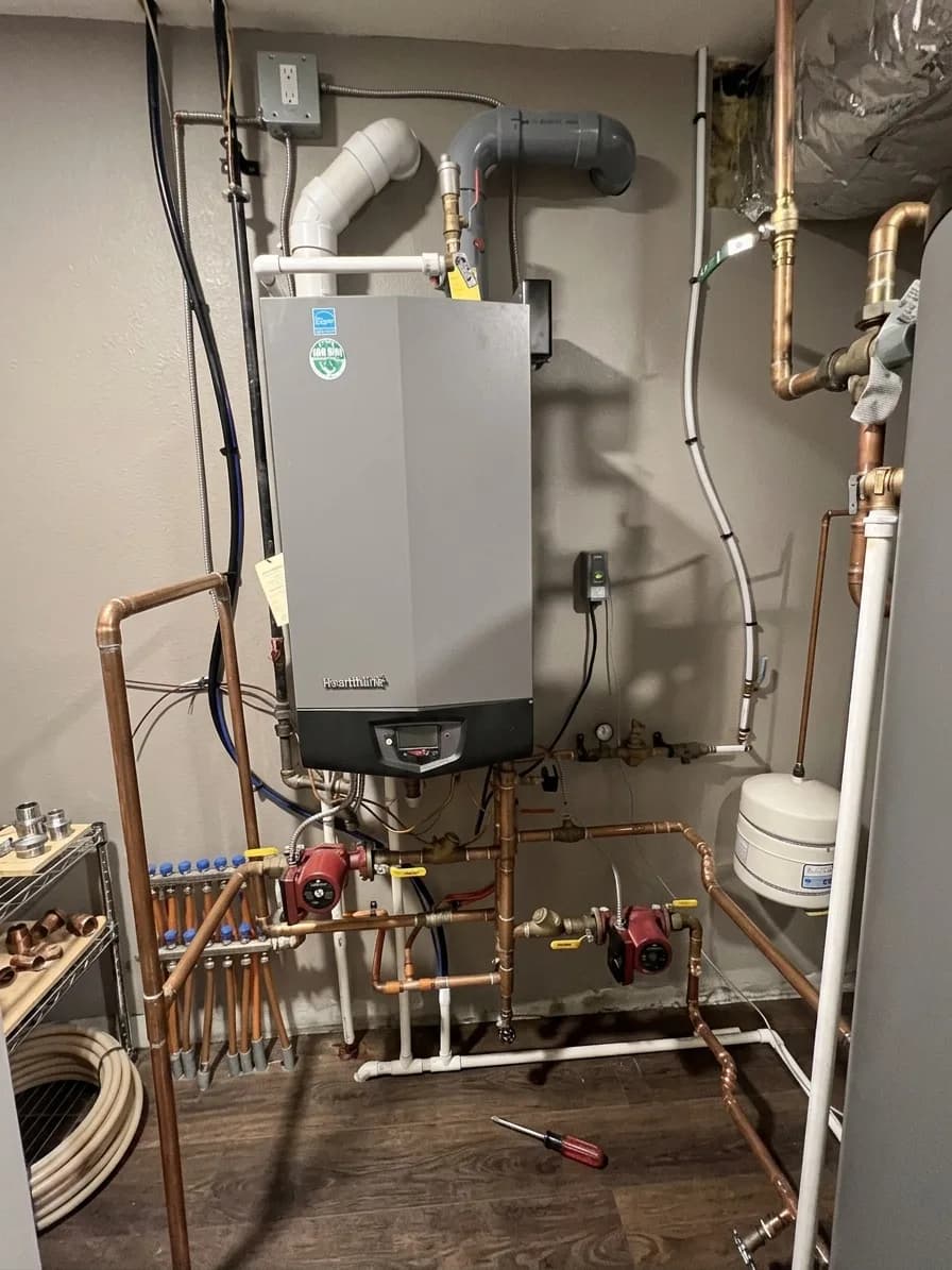 Tankless boiler installation with copper supply and PVC venting.